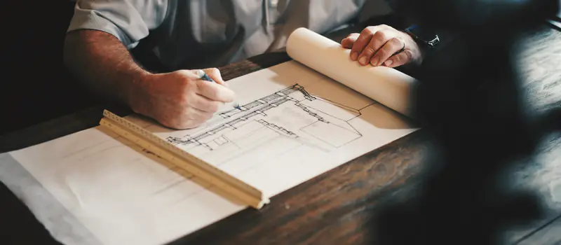 An architect drawing a plan by hand with a pencil and a ruler